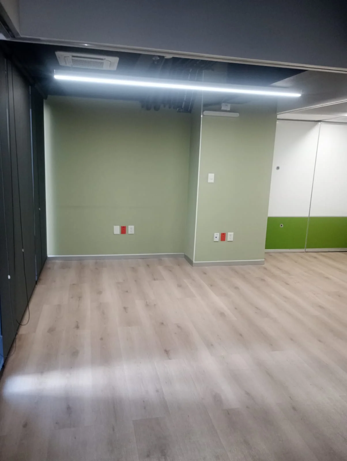 Espacio interior con muros verdes e iluminación lineal